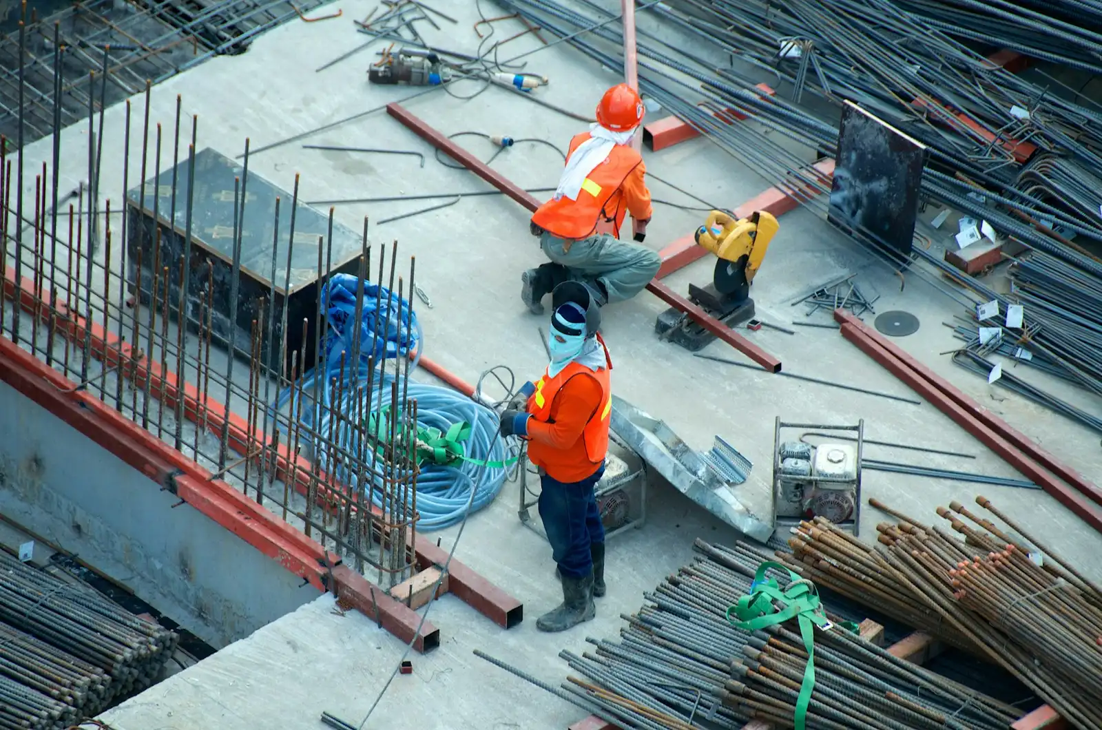 Workers laying steel reinforcement on a construction site, seen from above