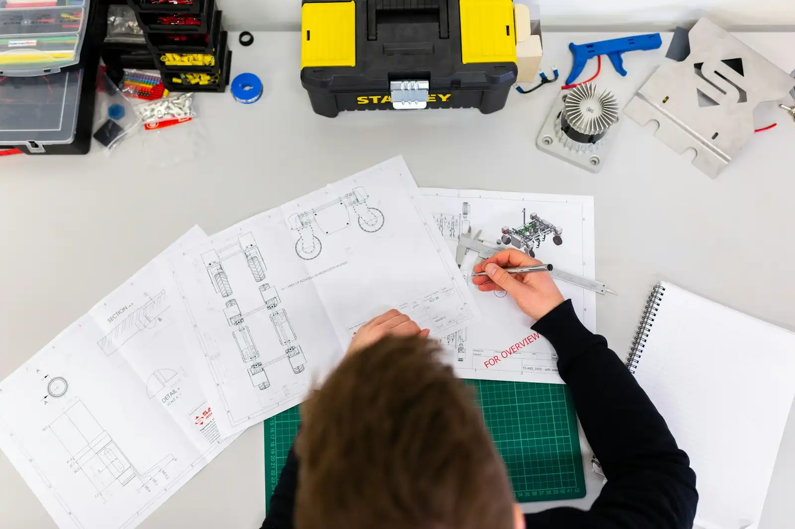Overhead view of technical drawings being reviewed and annotated on a desk