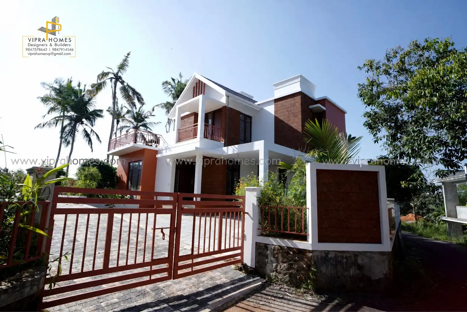 A VIPRA HOMES residence seen through its gate, with laterite-brick cladding and white upper storey