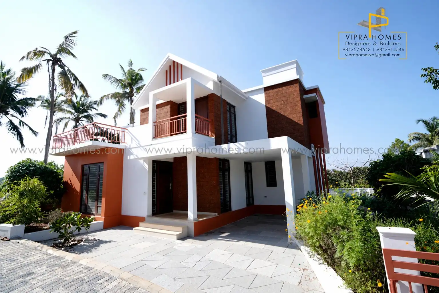 Corner view of a VIPRA HOMES residence with laterite-brick columns, terracotta walls and a gabled front