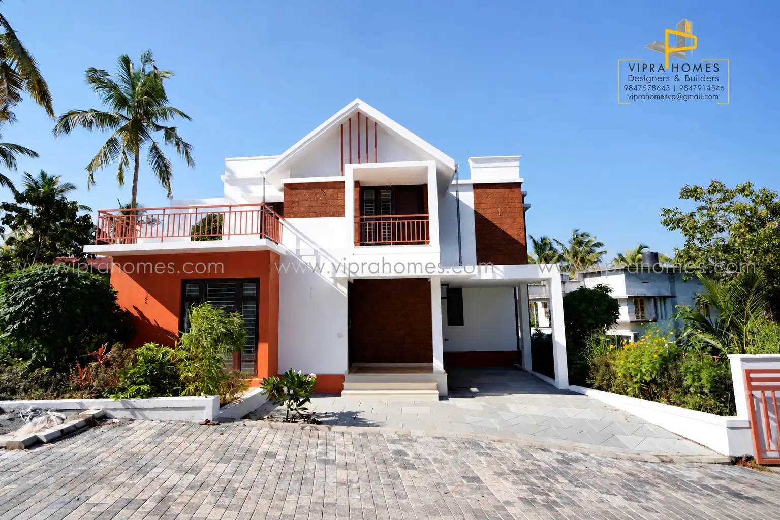 Front elevation of a VIPRA HOMES residence with a gabled roof, laterite-brick panels and a paved driveway