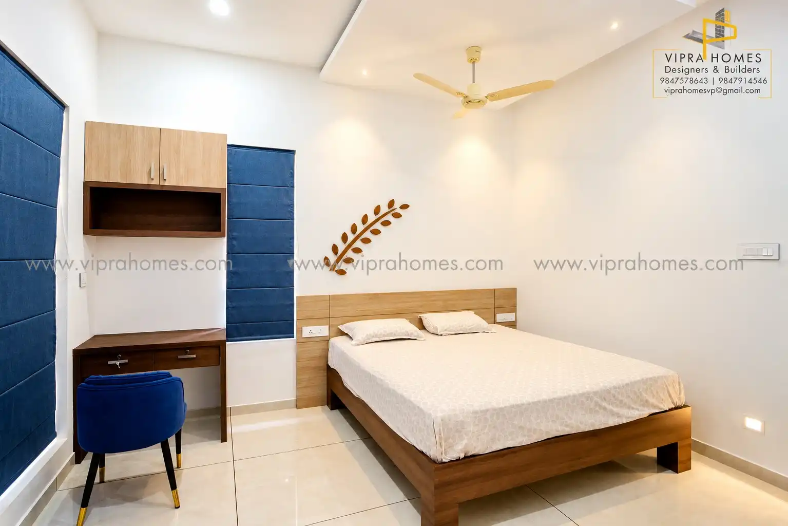 A bedroom by VIPRA HOMES with a timber bed, study desk, wall cabinet and blue blinds