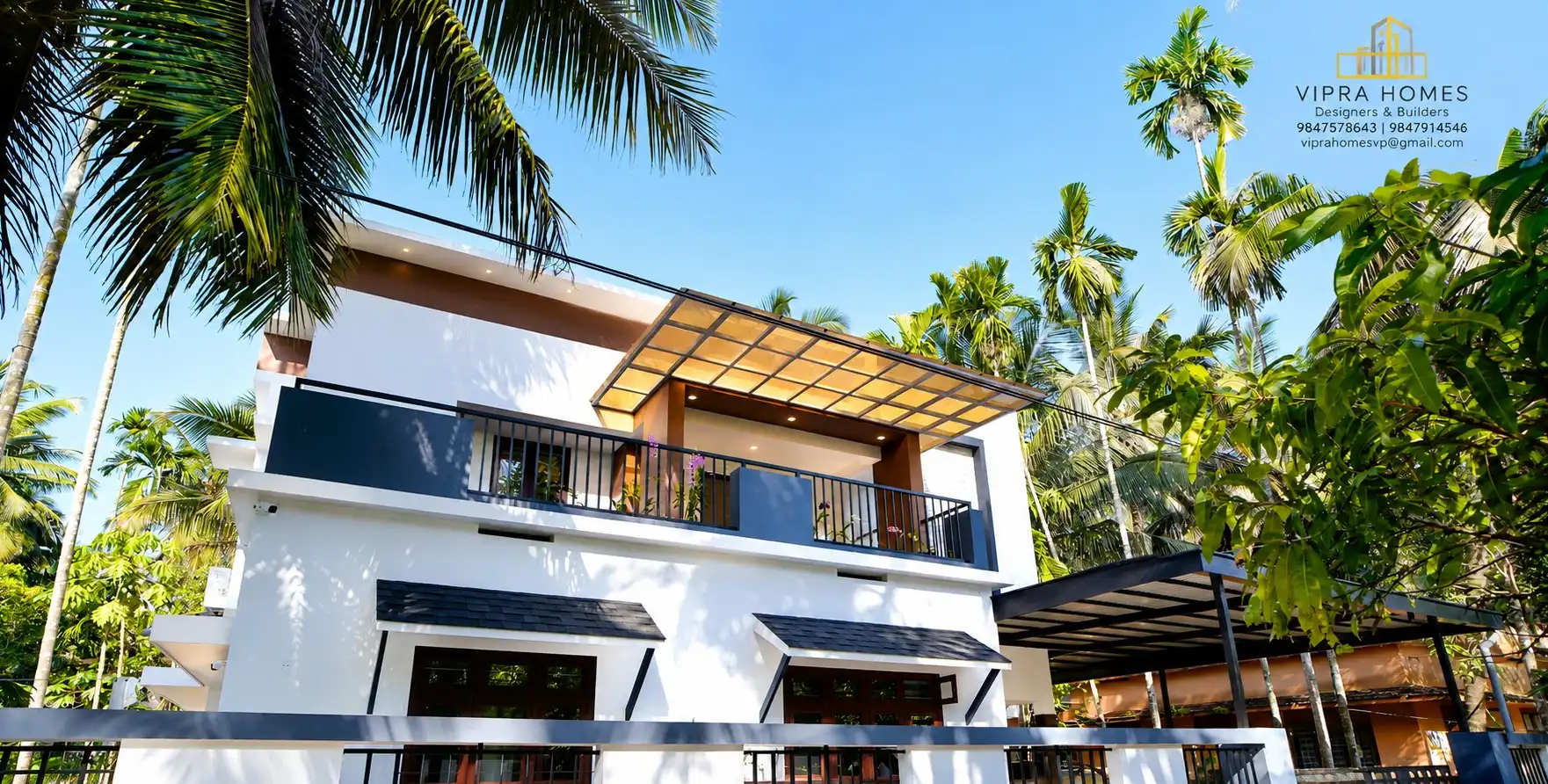 A contemporary white VIPRA HOMES residence with dark window canopies and a glazed balcony roof among palms
