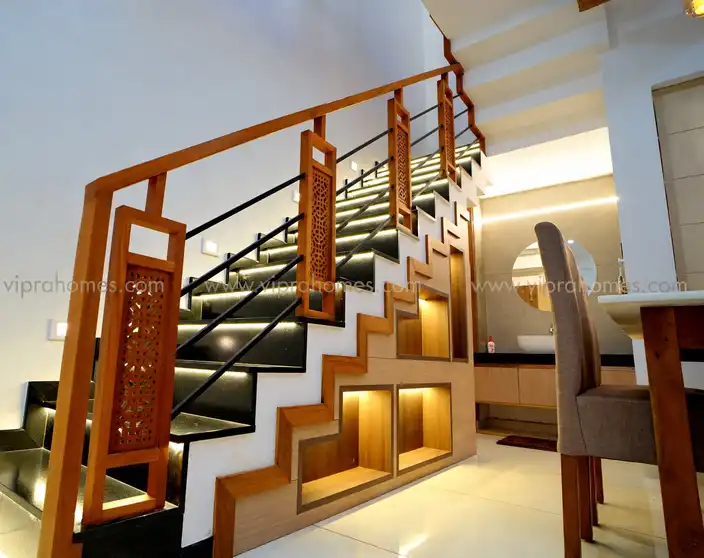 A staircase by VIPRA HOMES with carved timber balusters, black granite treads and lit display niches