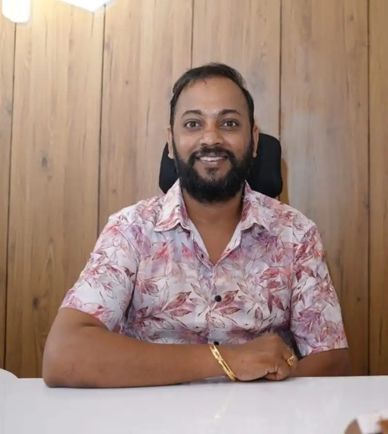 Praveen, co-founder of VIPRA HOMES, seated at a desk in front of timber wall panelling