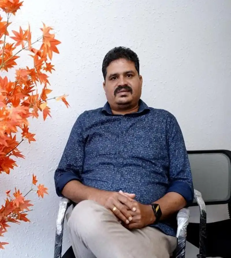 Vipin, co-founder of VIPRA HOMES, seated in the VIPRA office beside orange autumn-leaf decor